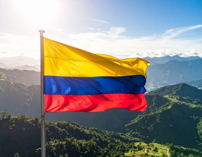 Bandera de Colombia ondeando sobre las montañas andinas